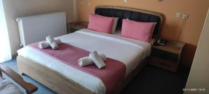 a bedroom with a large bed with pink pillows at Hili Hotel in Alexandroupoli