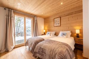 two beds in a room with a window at Chalet du Tricot - Vue sur le Mont Blanc in Saint-Gervais-les-Bains