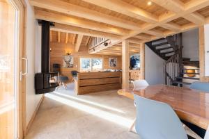 a dining room with a wooden table and white chairs at Chalet du Tricot - Vue sur le Mont Blanc in Saint-Gervais-les-Bains