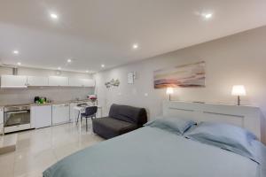 a white bedroom with a large bed and a kitchen at Studio cosy - 35m2 - Paris -Disneyland - Rer A in Noisy-le-Grand