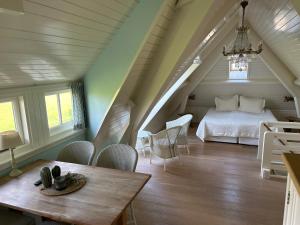 1 dormitorio con 1 cama, mesa y sillas en Villa Nieuwland B&B en Den Oever