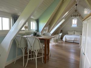 ein Esszimmer mit einem Tisch, Stühlen und einem Bett in der Unterkunft Villa Nieuwland B&B in Den Oever