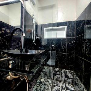 a bathroom with a sink and a black tiled wall at Residência Thomas in Itacaré