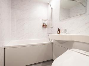 a white bathroom with a sink and a toilet at the b sapporo in Sapporo