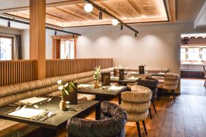 a dining room with tables and chairs and a couch at Lechquell Hotel Post in Steeg