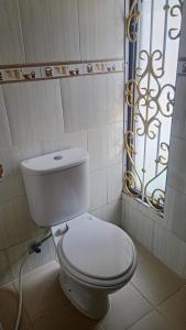 a white toilet in a bathroom with a window at Arsya Bagas Villa in Bogor