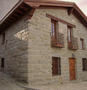 ナバルエンガにあるEl Mirador del Alberche 1の窓2つとバルコニー2つが備わる石造りの建物