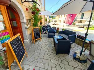 an outdoor patio with chairs and tables and an umbrella at Garni Hotel Bovec in Bovec