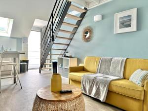 - un salon avec un canapé jaune et des escaliers dans l'établissement Le Patio de Loiseau, au Mans