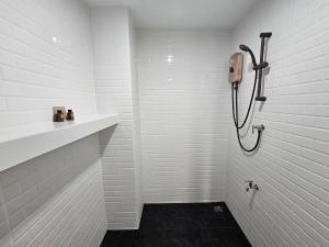 een witte badkamer met een douche en een wastafel bij โรงแรมแอเรียเพลส สาทร (AREA Place) in Chong Nonsi