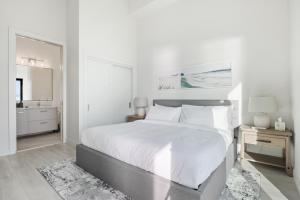 a white bedroom with a large bed and a bathroom at Beachfront Luxury Suite #15 at THE BEACH HOUSE in Campbell River