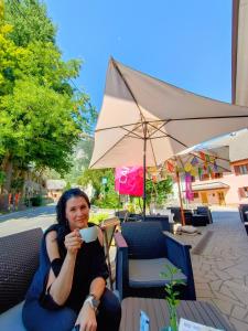 Eine Frau, die auf einem Tisch sitzt und eine Tasse Kaffee hält. in der Unterkunft Garni Hotel Bovec in Bovec