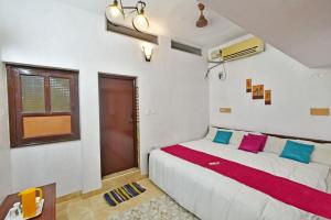 1 dormitorio con 1 cama blanca grande con almohadas coloridas en Coral Home Stay, en Pondicherry