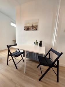 une table blanche et deux chaises dans une pièce dans l'établissement Superbe 2 pièces rénové et calme, à Aubervilliers
