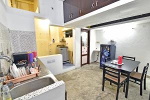 uma cozinha com um lavatório e uma mesa com cadeiras em Coral Home Stay em Pondicherry