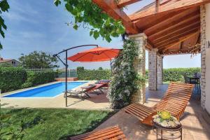 un patio con sillas y una sombrilla junto a la piscina en Villa Sunset, en Bužinija