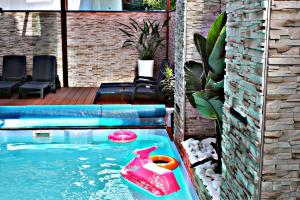 a swimming pool with a pink inflatable raft in the water at Willa Exotic kryty basen in Łeba