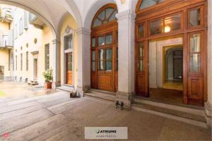 een hond die voor een grote houten deur zit bij Atriums Apartment Giambattista Bogino in Turijn