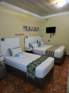 a hotel room with two beds and a flat screen tv at At Blackwood Guesthouse in Pretoria