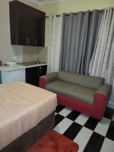 a room with a bed and a chair and a kitchen at At Blackwood Guesthouse in Pretoria