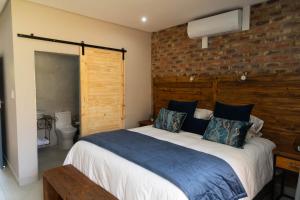 a bedroom with a large bed and a brick wall at Opstal Gastehuis in Potchefstroom