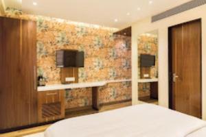 um quarto de hotel com uma cama e uma televisão em Hotel Sangat Regency em Bhopal