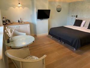 1 dormitorio con cama, mesa, mesa y sillas en Villa Nieuwland B&B, en Den Oever