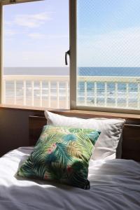 a bed with a pillow in front of a window at Hotel NALU　ホテルナル in Kannoura