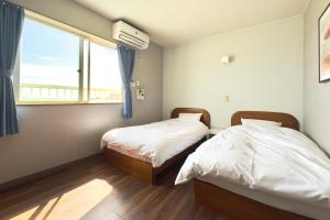 two beds in a room with a window at Hotel NALU　ホテルナル in Kannoura
