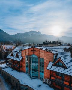 a building covered in snow with mountains in the background at Hotel Wersal in Zakopane