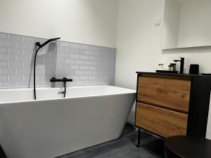 a white bath tub in a bathroom with a sink at The Originals Boutique, Hôtel Le George , Loches in Loches