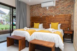 2 camas en un dormitorio con una pared de ladrillo en Opstal Gastehuis, en Potchefstroom