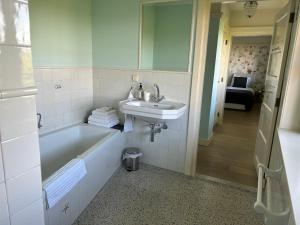 a bathroom with a sink and a bath tub and a sink at Villa Nieuwland B&B in Den Oever