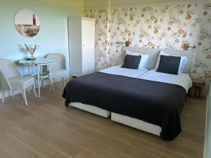 1 dormitorio con 1 cama con mesa y sillas en Villa Nieuwland B&B en Den Oever