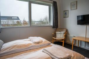 ein Schlafzimmer mit einem Bett, einem Fenster und einem Stuhl in der Unterkunft Hotel Herning in Herning