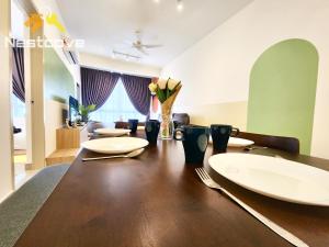 a dining room table with white plates and flowers on it at Mutiara Bali Residence Suites By Nestcove in Melaka