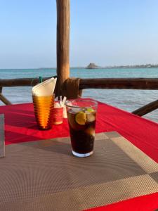 a drink sitting on a table next to the ocean at Malcom Residence in Pongwe