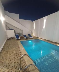 una piscina con 2 sillas azules junto a un edificio en Villa Dream Desert, en Luxor
