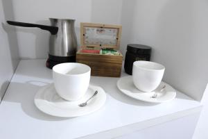 two white cups and saucers sitting on a counter at Luxury Suite - Teatro Romano - Duomo - Centro Storico Wi-Fi in Terracina