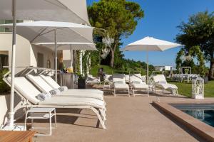 a group of lounge chairs and umbrellas next to a pool at Villa Belvedere in Bertinoro