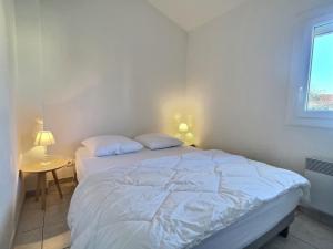 uma cama branca num quarto com uma janela em Petit pavillon pour 6 personnes dans une résidence avec piscine em Valras-Plage