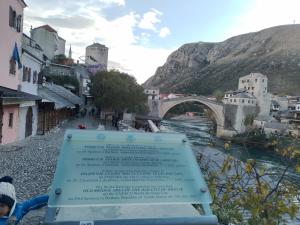 ein Schild neben einem Fluss mit einer Brücke in der Unterkunft Guesthouse Sanja - Apartments 212 in Mostar