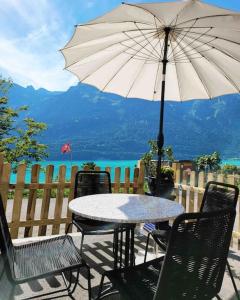 uma mesa e cadeiras com um guarda-sol num pátio em Lakeview Basement Apartment near Interlaken em Niederried
