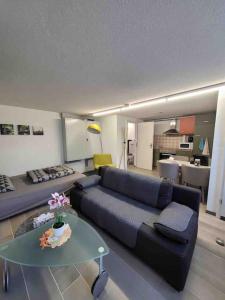 uma sala de estar com um sofá azul e uma mesa em Lakeview Basement Apartment near Interlaken em Niederried