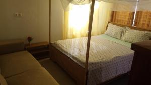 1 dormitorio con cama con dosel y sofá en Vue sur l'Atlantique, en Cotonou
