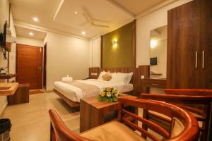 une chambre d'hôtel avec un lit, une table et des chaises dans l'établissement ARIAT AVENUE, à Wayanad