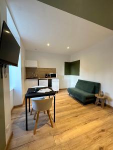 ein Wohnzimmer mit einem Tisch und einem grünen Sofa in der Unterkunft Limoges Sud-LesCinqSuites Le Saint Laurent-DABNB in Limoges