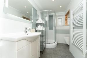 ein weißes Bad mit einem Waschbecken und einer Dusche in der Unterkunft Haus Attos in Umhausen