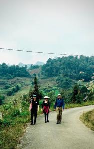 Un groupe de trois personnes marchant sur une route dans l'établissement Bac Ha Lodge Retreat, à Bắc Hà
