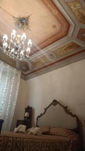 a bedroom with a ceiling with a chandelier and a bed at Relais Corso Storico in Pisa